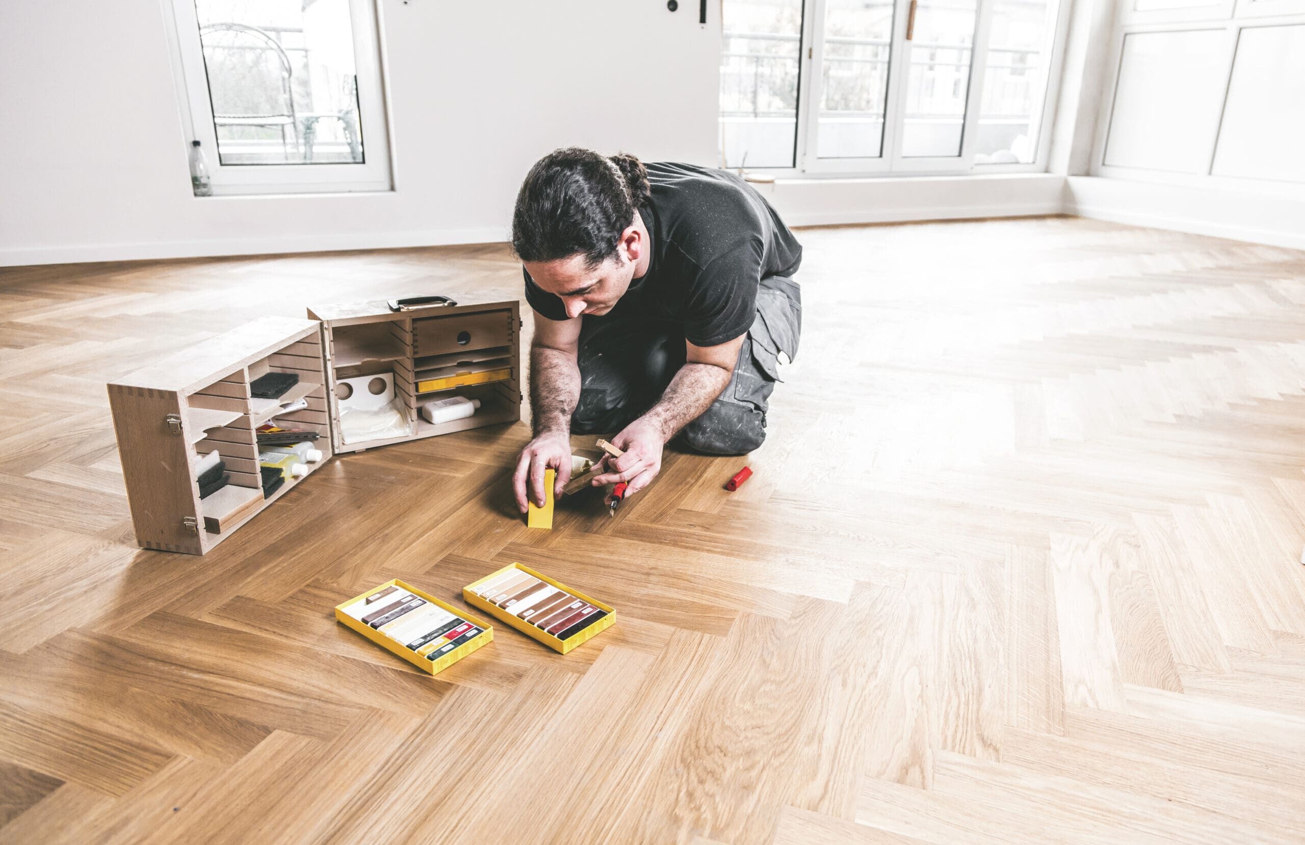 Fachmännische Reparatur und Ausbesserung eines Parkettbodens mit speziellen Holzfüllern und Werkzeugen.